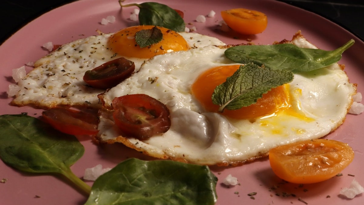 Fried eggs are served with tomatoes and herbs.